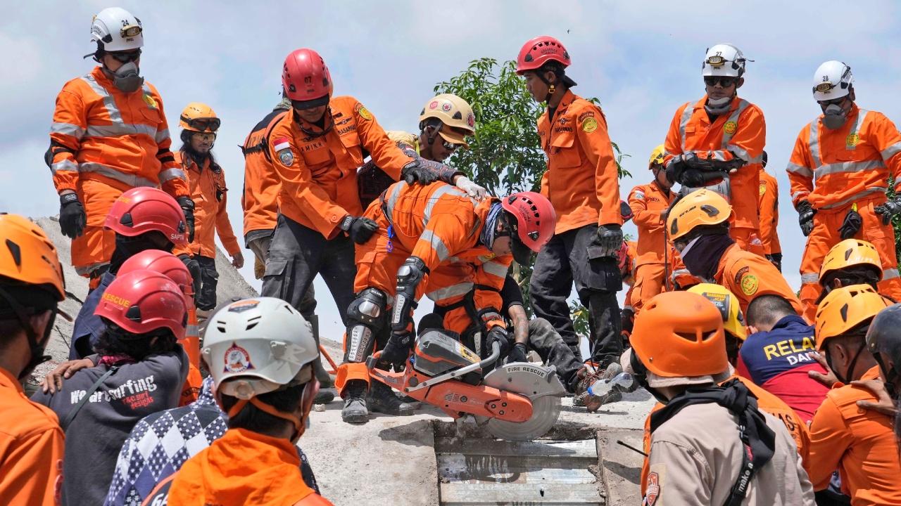 Rescuers recover the body of an earthquake victim from under the rubble of a collapsed building in Cianjur