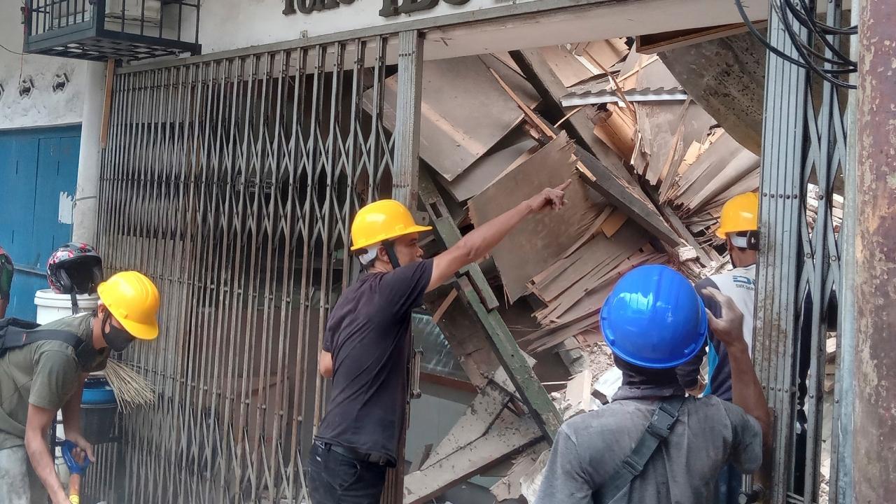 Workers inspect a store damaged during an earthquake in Cianjur