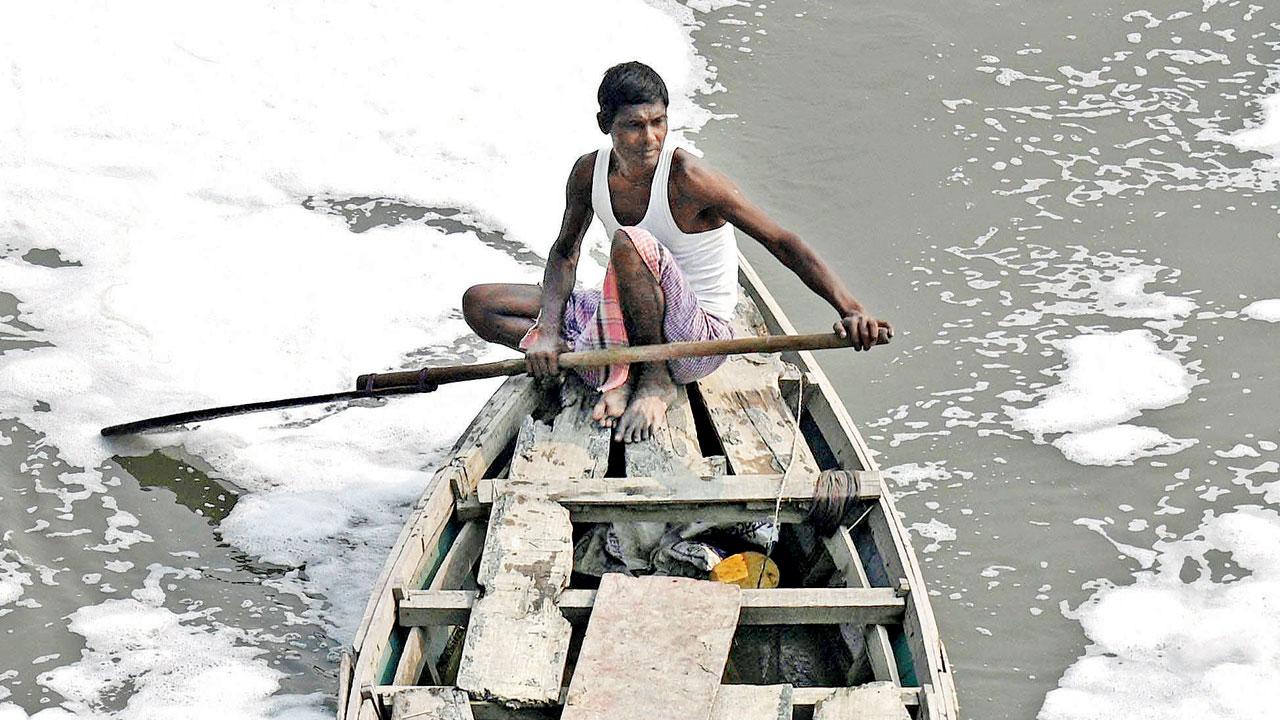 Boatmen steer a boat along the polluted waters of the Yamuna river in Delhi on Friday. Officials are spraying river surface with chemicals to treat toxic foam for Chhath puja. Pic/AFP