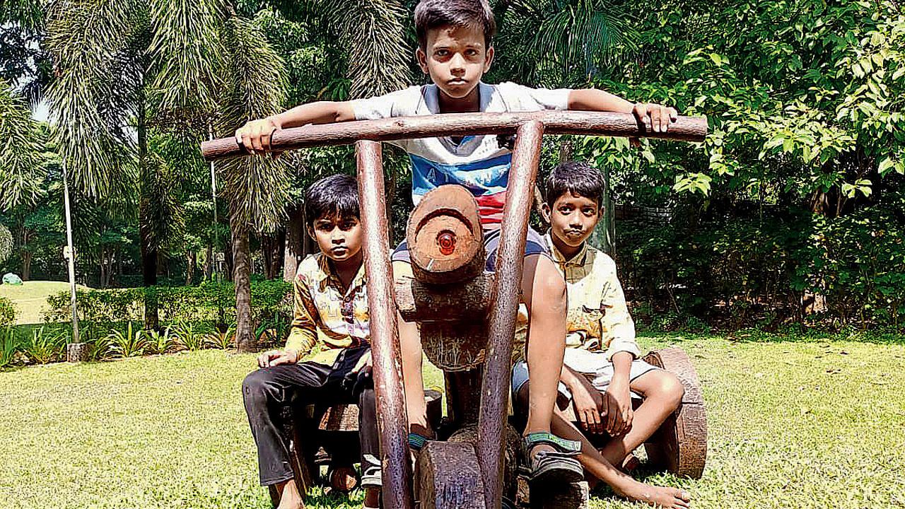 Three boys pose on the wooden bike for a picture