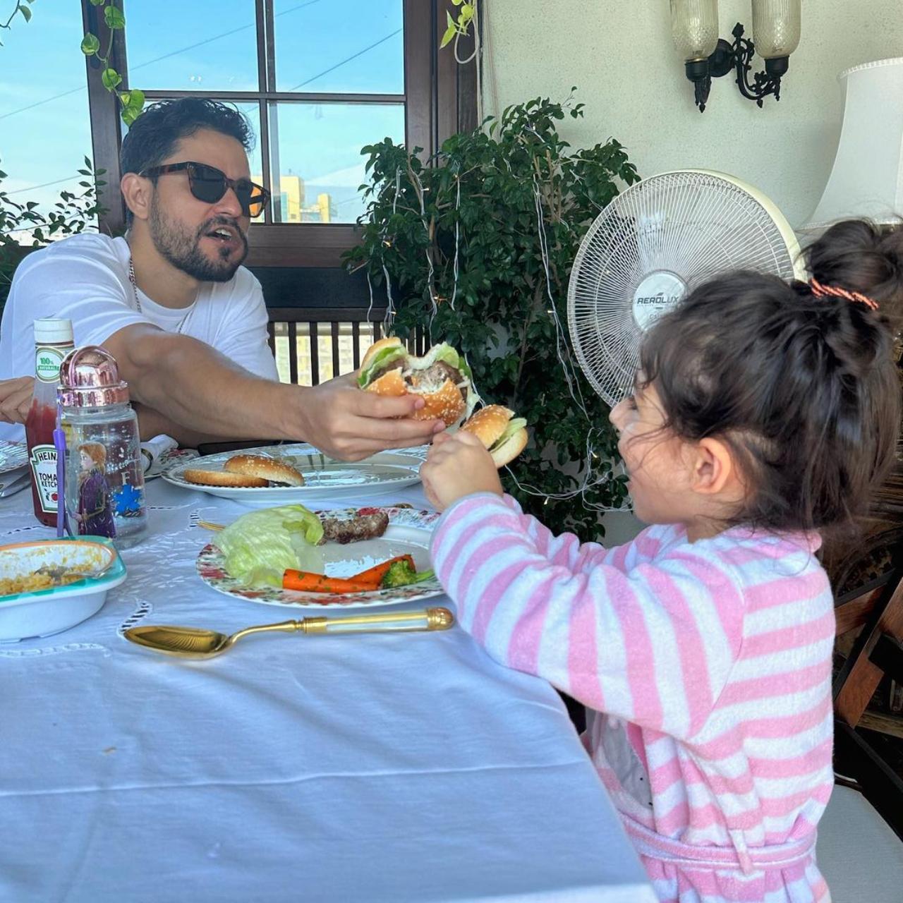 In one of the pictures shared by Soha, Kunal can be seen helping his daughter Inaaya with a bite of burger