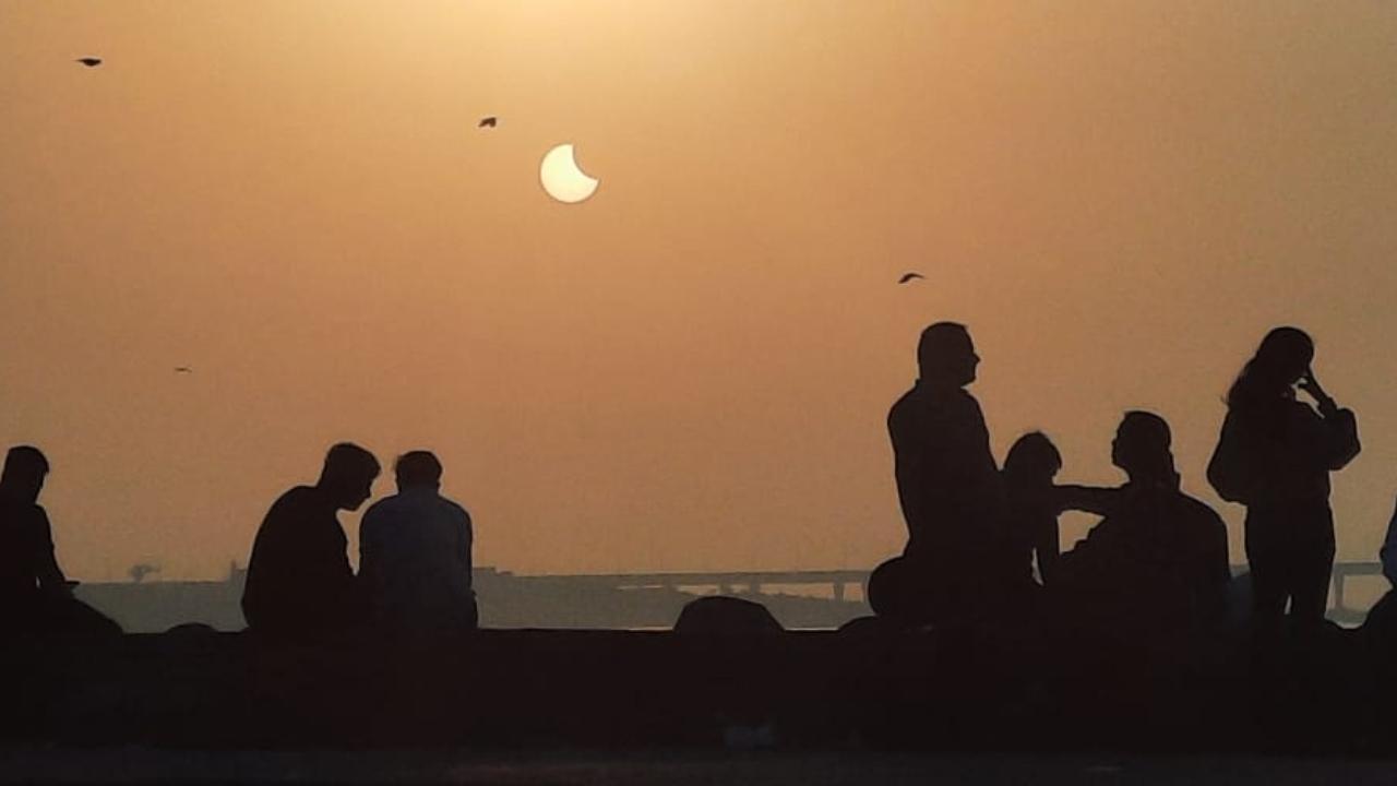 Mumbaikars enjoy the partial solar eclipse or Surya Grahan at Dadar Beach. Pic/Pradeep Dhivar