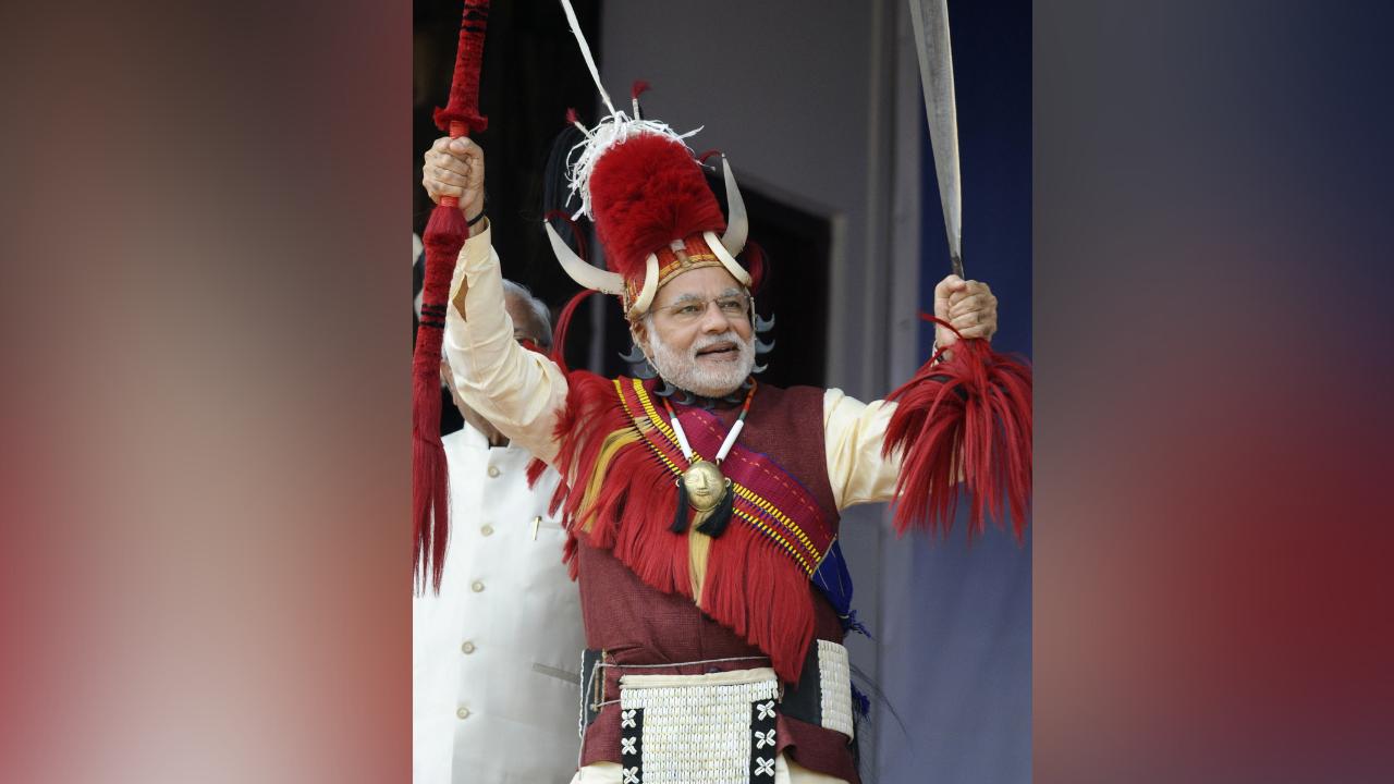 Indian Prime Minister Narendra Modi, clad in Naga tribal costume, poses with a tribal Naga spear and a traditional machete (dao) during the inauguration of the Hornbill Festival at Kisama in the outskirts of Kohima, the capital city of India’s northeastern state of Nagaland, on December 1, 2014. Photo Courtesy: AFP