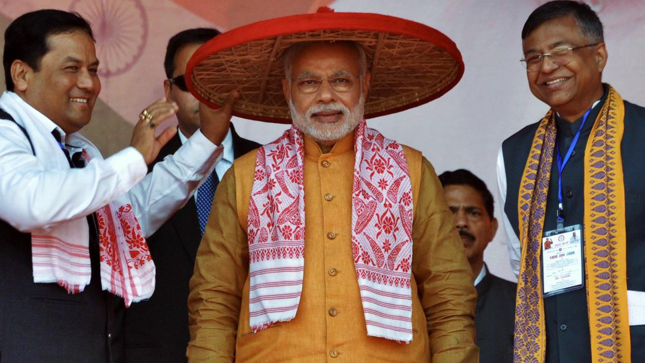 Indian Prime Minister Narendra Modi is presented with a trasitional Assamese hat known as a 'Japi' by Bharatiya Janata Party (BJP) leaders at a party rally in Guwahati on November 30, 2014. Photo Courtesy: AFP