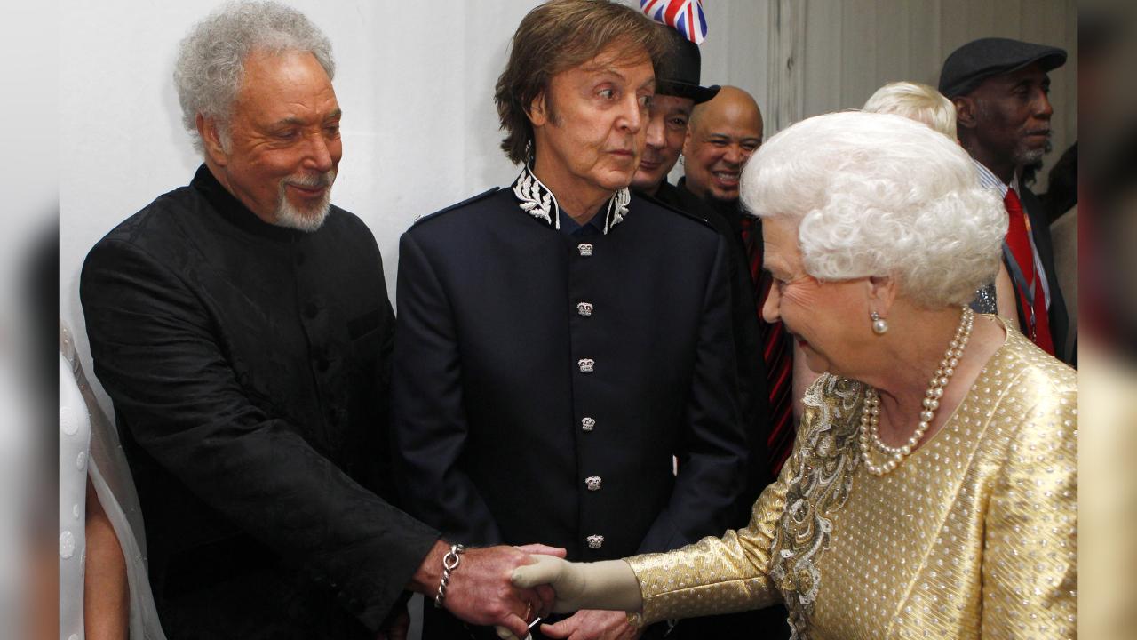 Queen Elizabeth II greets British singers Sir Tom Jones (left) and Paul McCartney backstage during the Diamond Jubilee Concert outside Buckingham Palace in London, on June 4, 20112. (Photo by Dave Thompson / AFP)