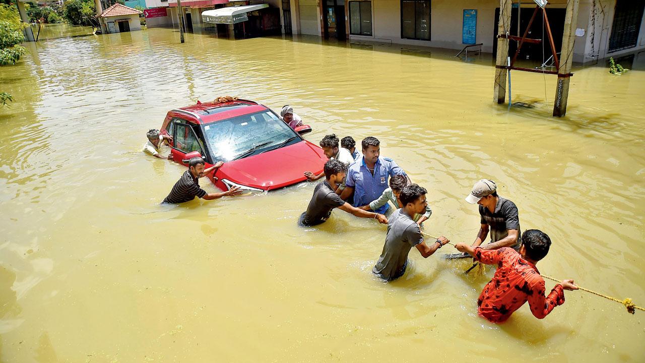 Rescuers try to pull out a car from flooded Rainbow Drive Layout. pic/pti