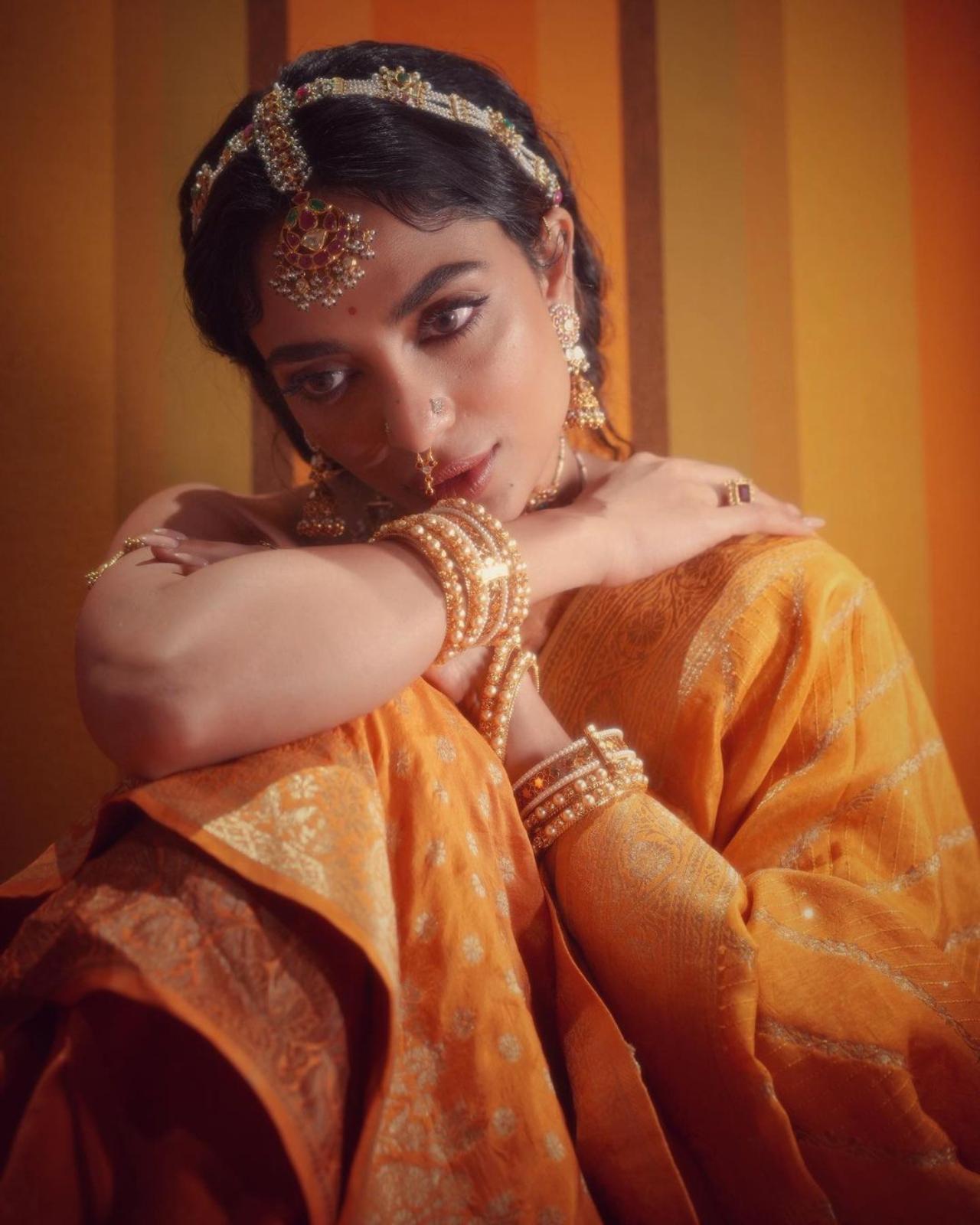 For the grand event in Chennai, Sobhita opted for a yellow silk saree. She wore it with an orange strapless brocade silk blouse with gold patterns with atie detail on the back. She completed the look with a mustard yellow dupatta. The saree was embellished with sequins