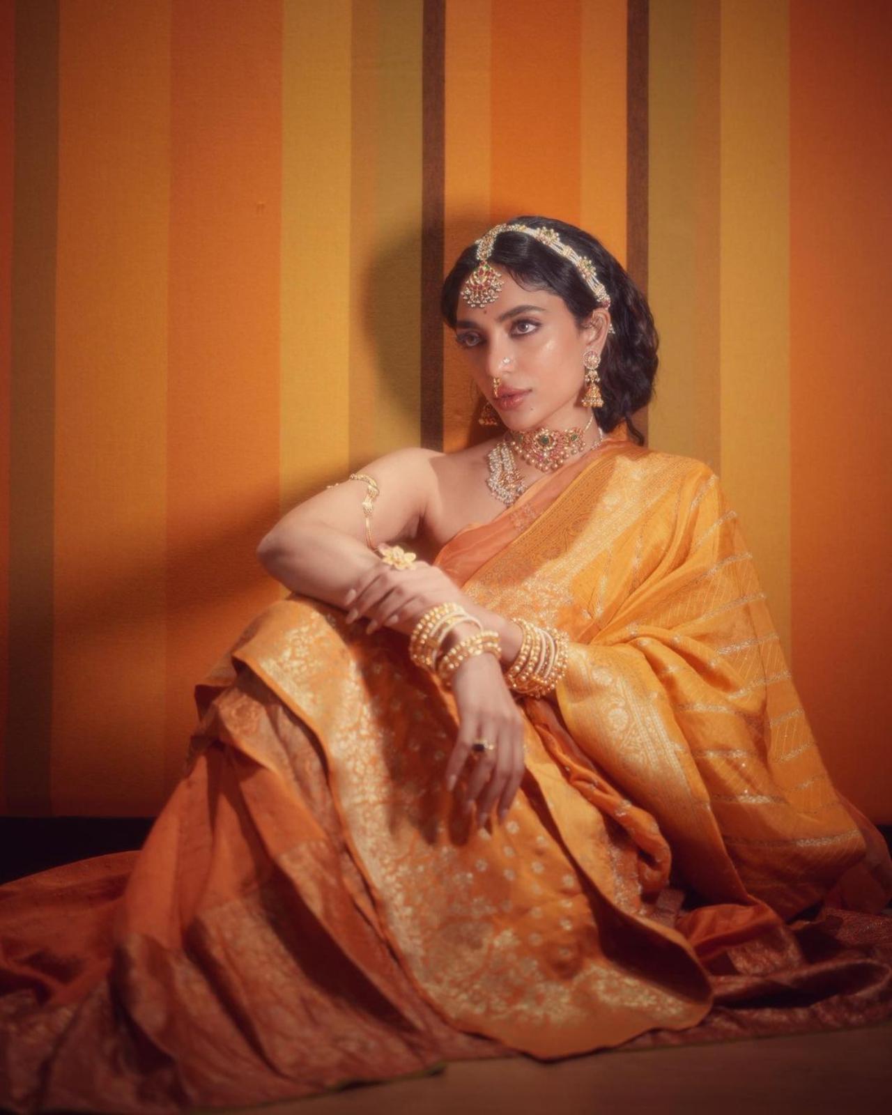 Sobhita cinched her pallu and the dupatta with her kamarband. She completed her look with heavy temple jewellery. From layered necklaces, mang tikka, matha patti, jhumkis, nath, rings, and bangles, the actress lived up to the theme of the film