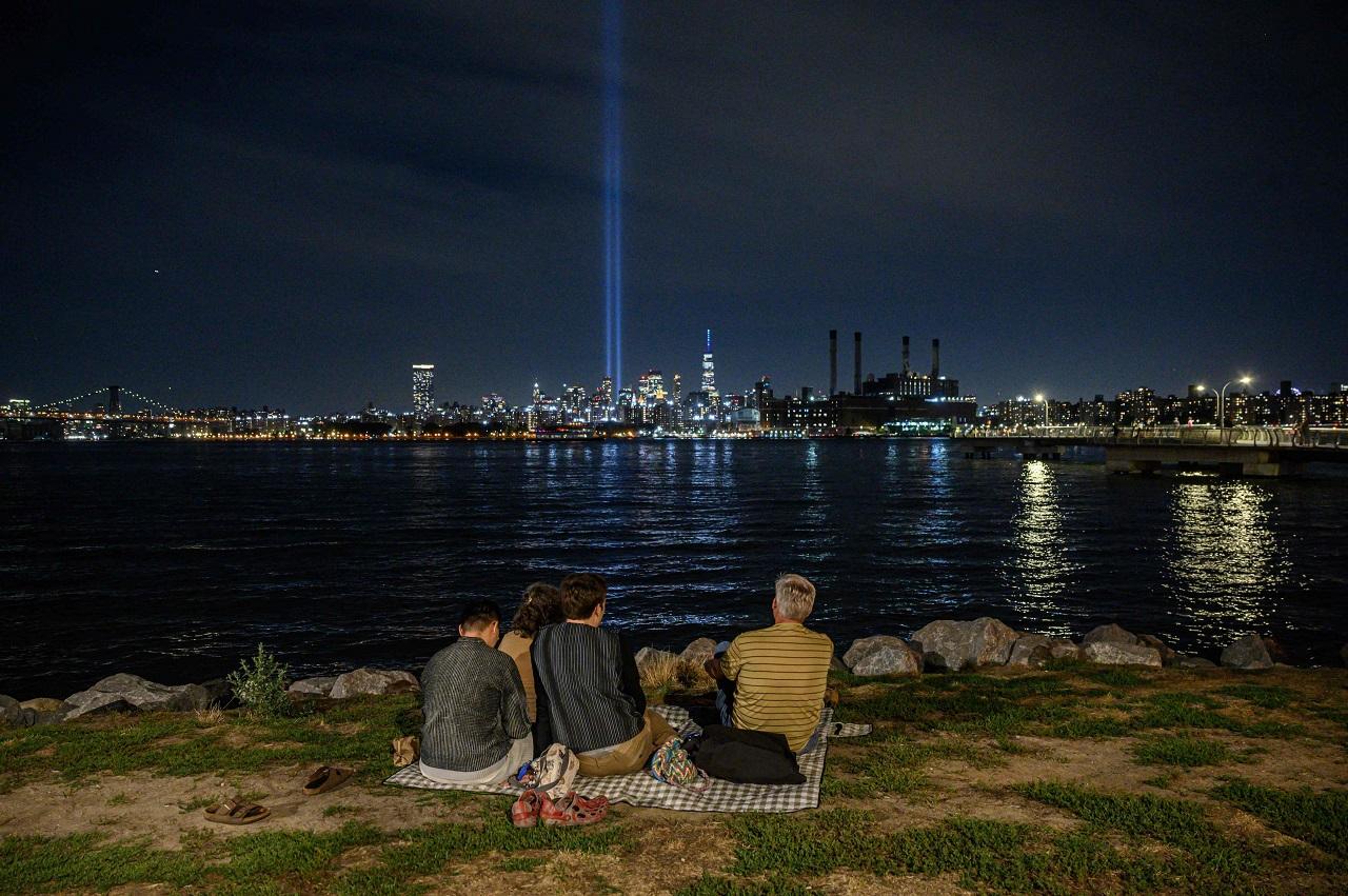 People sit before the east river and the 'Tribute in Light' installation amid the Manhattan city skyline commemorating the 9/11 terrorist attacks. (Pic/AFP)