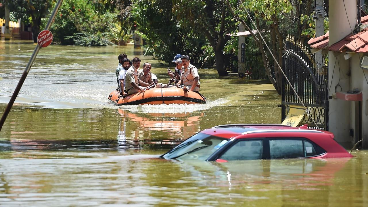 Rescuers try to pull out a car from flooded Rainbow Drive Layout after heavy monsoon rains at Sarjapur, in Bengaluru. Pic/PTI