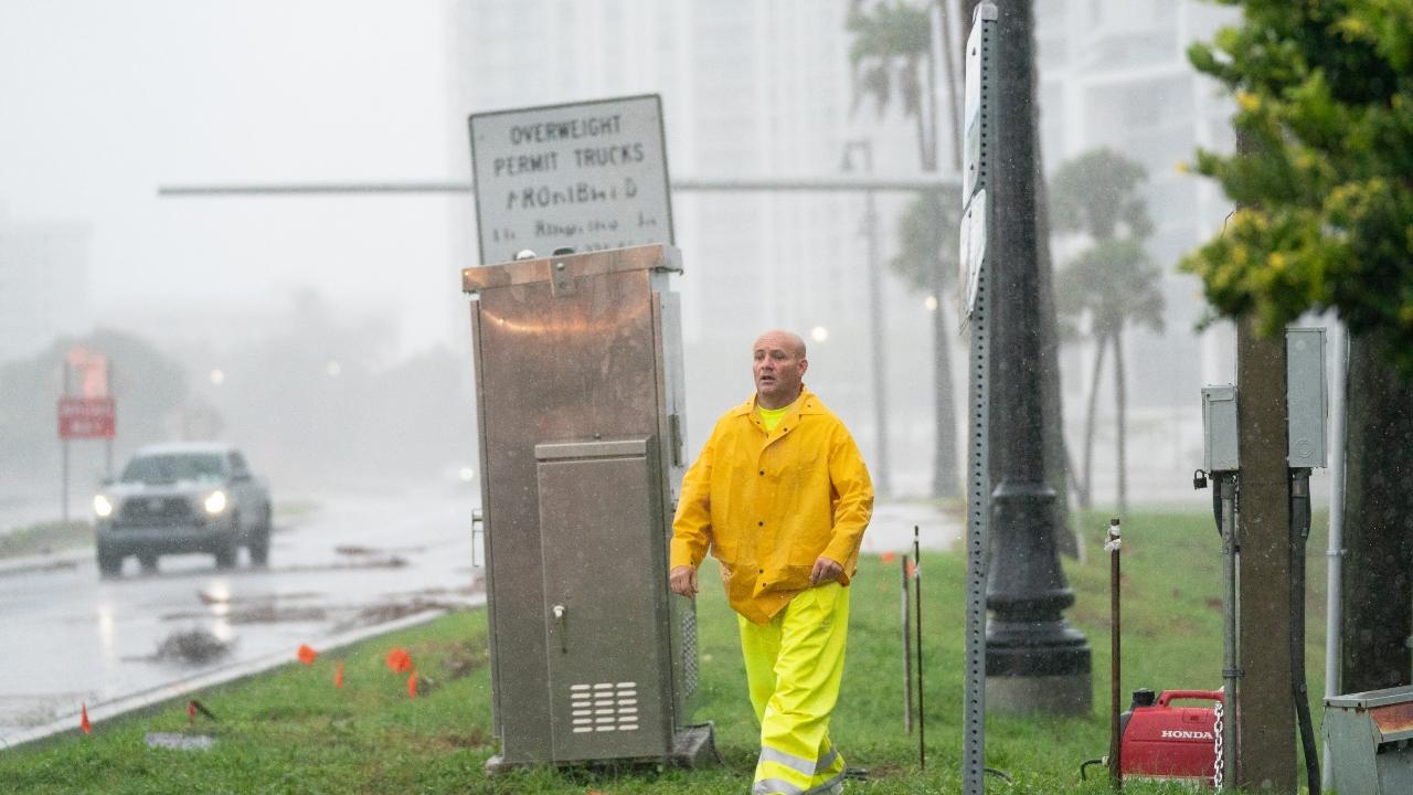 An emergency worker works deploys a generator to power a traffic signal as Hurricane Ian approaches