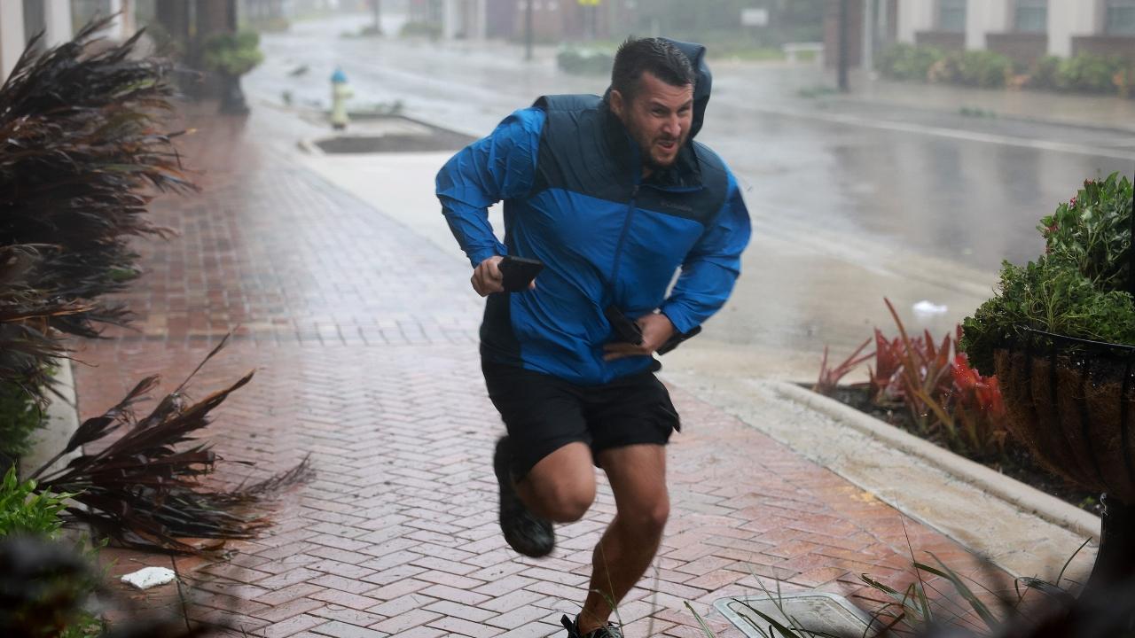 Brent Shaynore runs to a sheltered spot through the wind and rain from Hurricane Ian