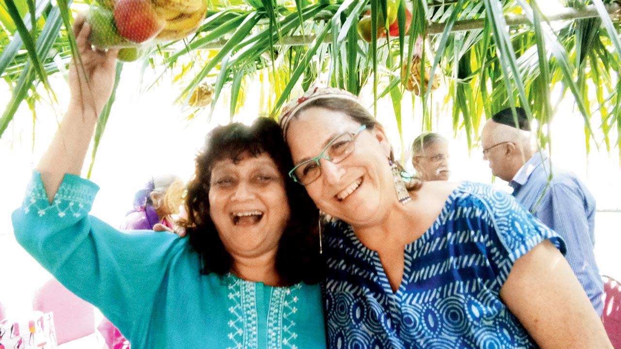 Rina Moses Rebello with Rabbi Edelman-Green under the sukkah, a booth-like hut woven with willow, palm and myrtle branches, where thanksgiving is offered for the  harvest feast