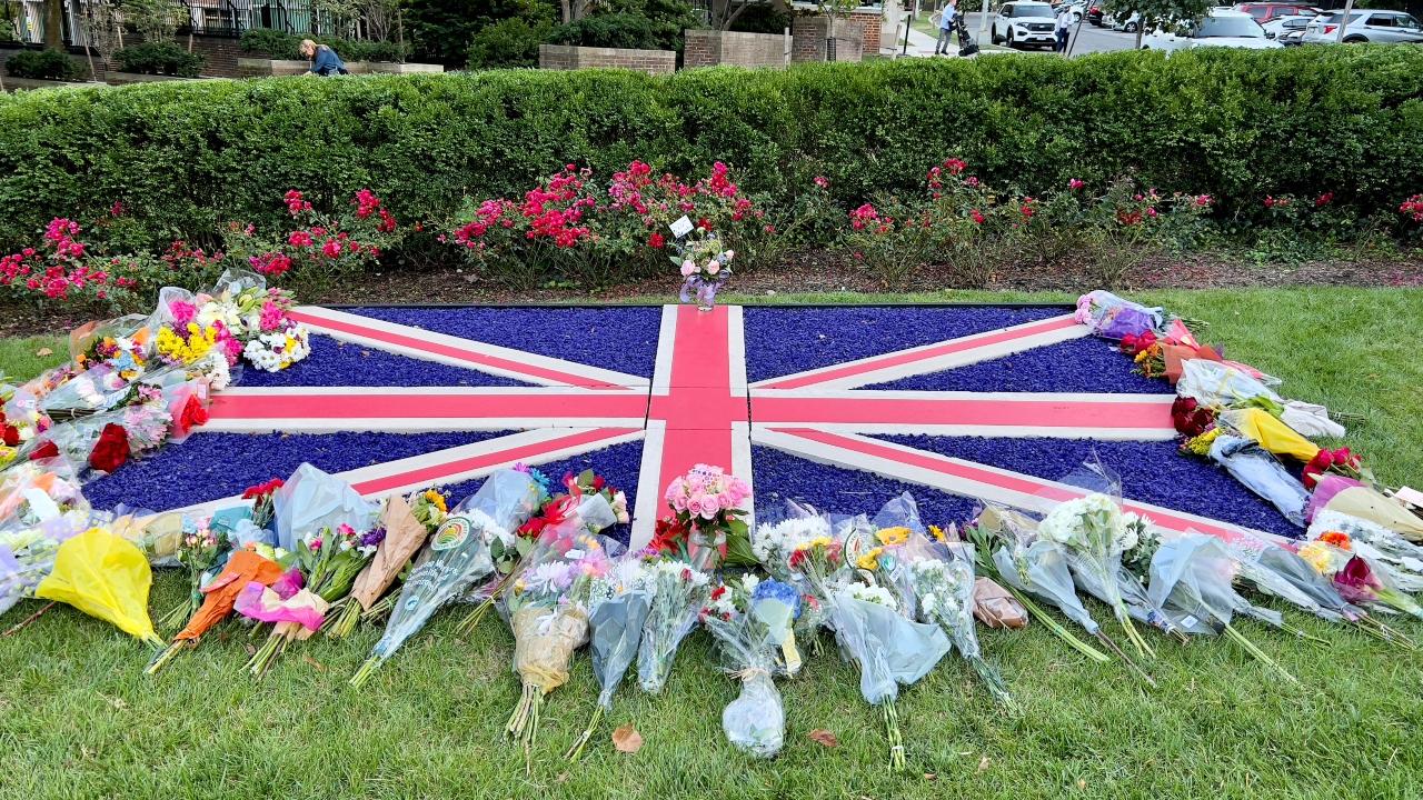 A British flag is pictured surrounded by flowers outside the British Embassy in Washington, DC