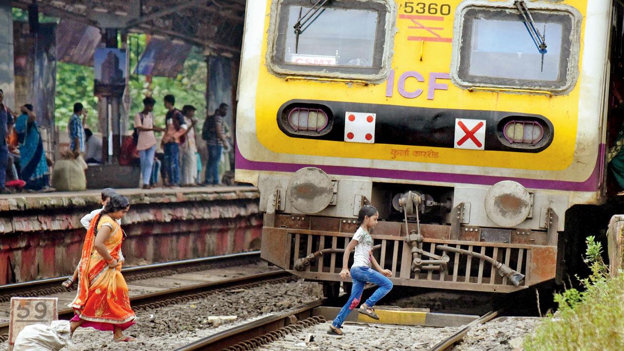 A woman holding a child and another kid run across the tracks at Ambivli railway station, on September 11, 2022. Pic/Sameer Markande