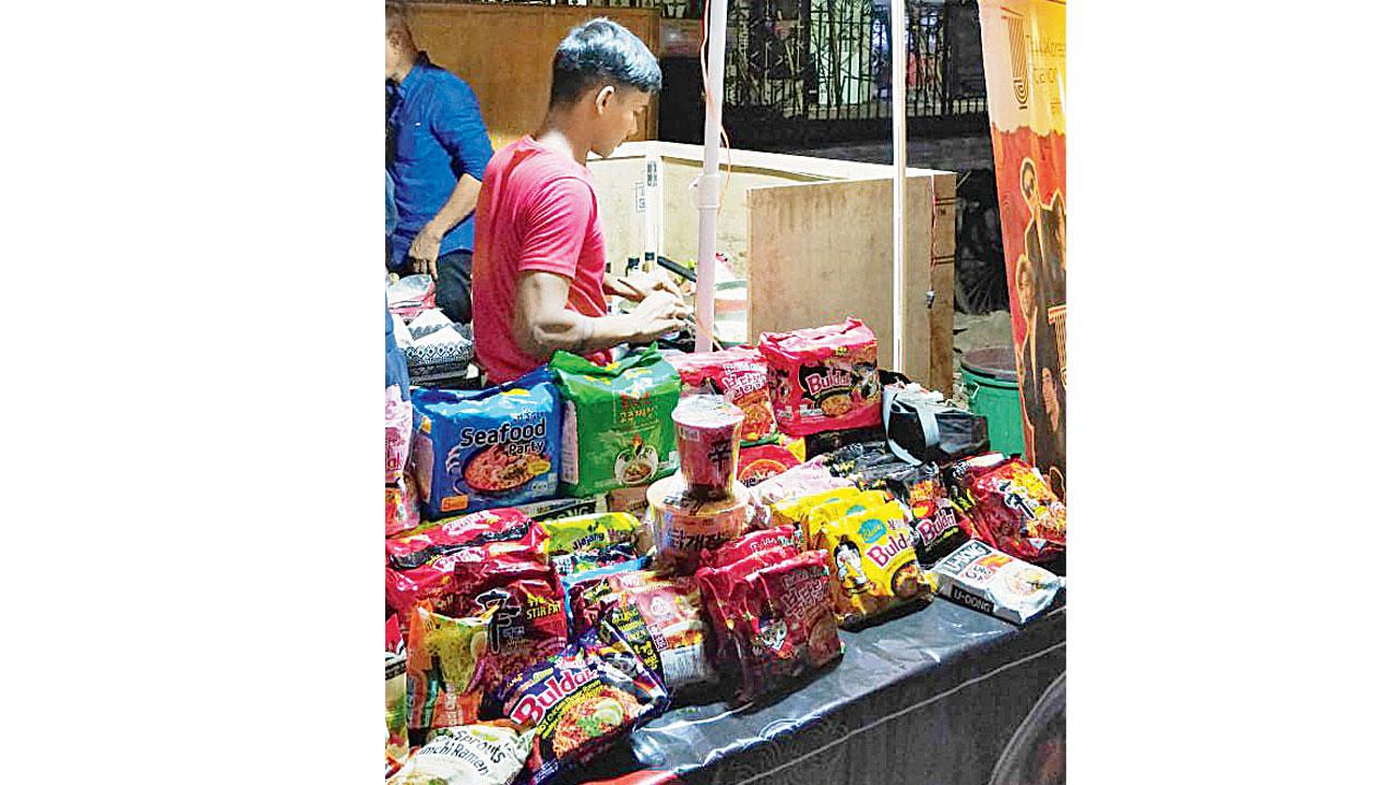 A staffer cooks noodles at the kiosk that displays many ramen options