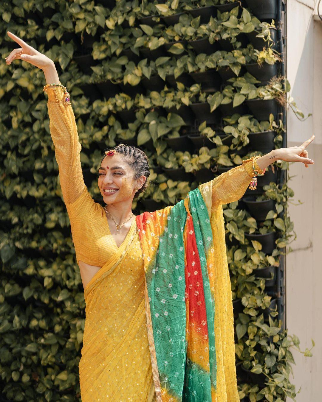The actress was dressed in a yellow saree and paired with a stunning baandhni dupatta, and she looked all ready and happy for the haldi and snaathakam ceremony. Her whole appearance was made more elegant by the elaborate motifs on her saree and the dupatta itself 