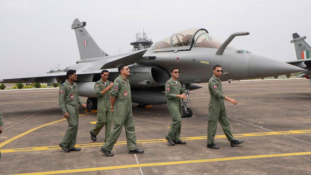 Indian Air Force (IAF) personnel walk past a Rafale fighter jet.