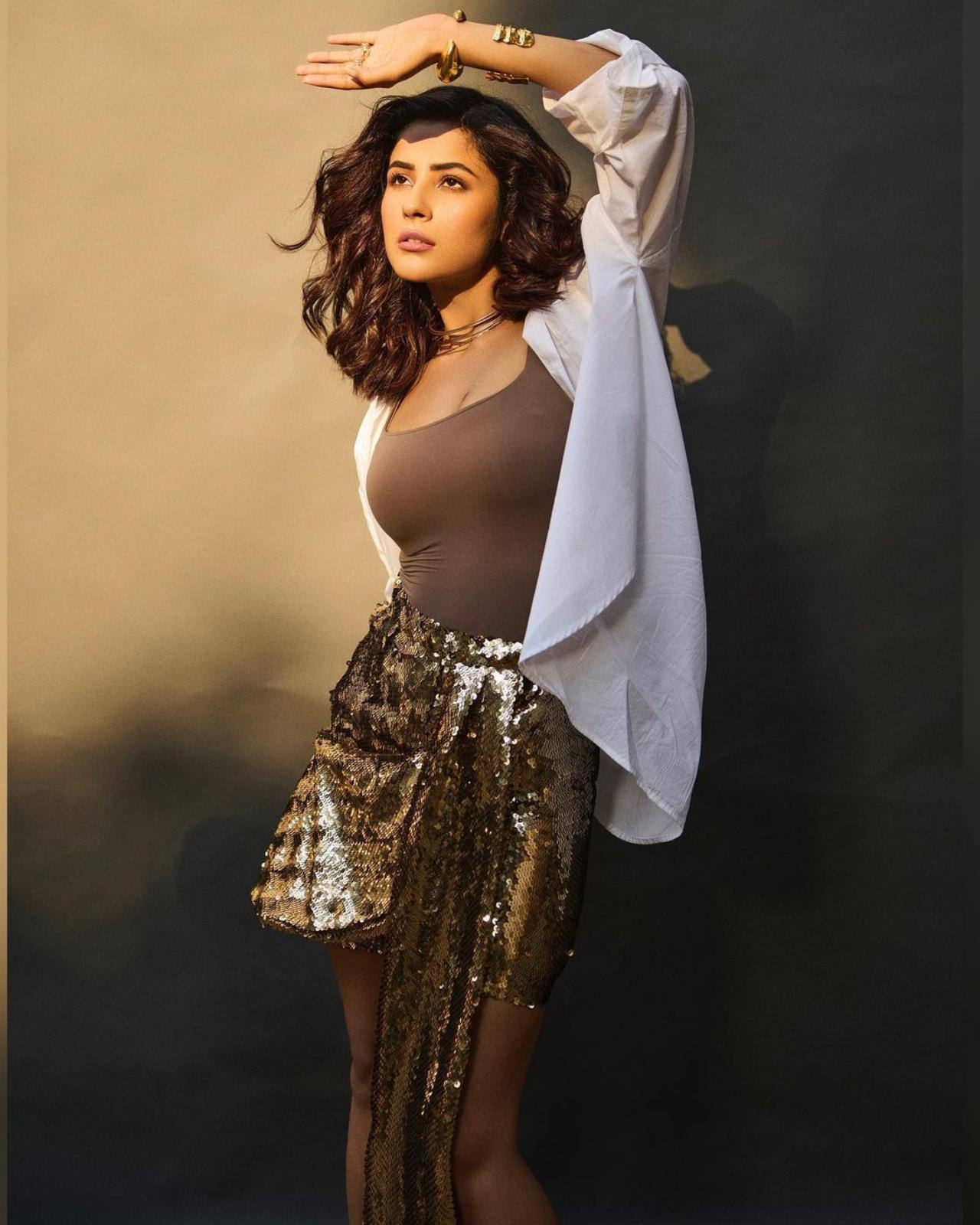 Because sequins never go wrong, Shehnaaz opted for a gold sequined skirt, paired with a brown tank top and a white shirt. The look was topped off with some gold chunky bracelets and wavy locs.