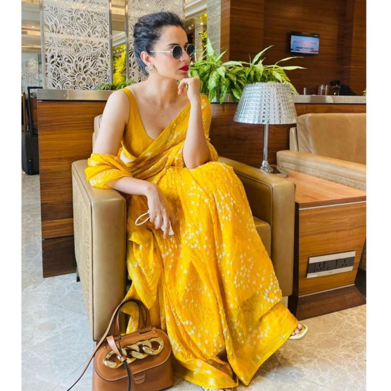 Kangana Ranaut
Kangana Ranaut, known for her saree style, recently sported a vibrant yellow bandhani saree at the airport. She paired it with a low-cut, sleeveless blouse, complemented by striking earrings and red lipstick, exuding chic elegance