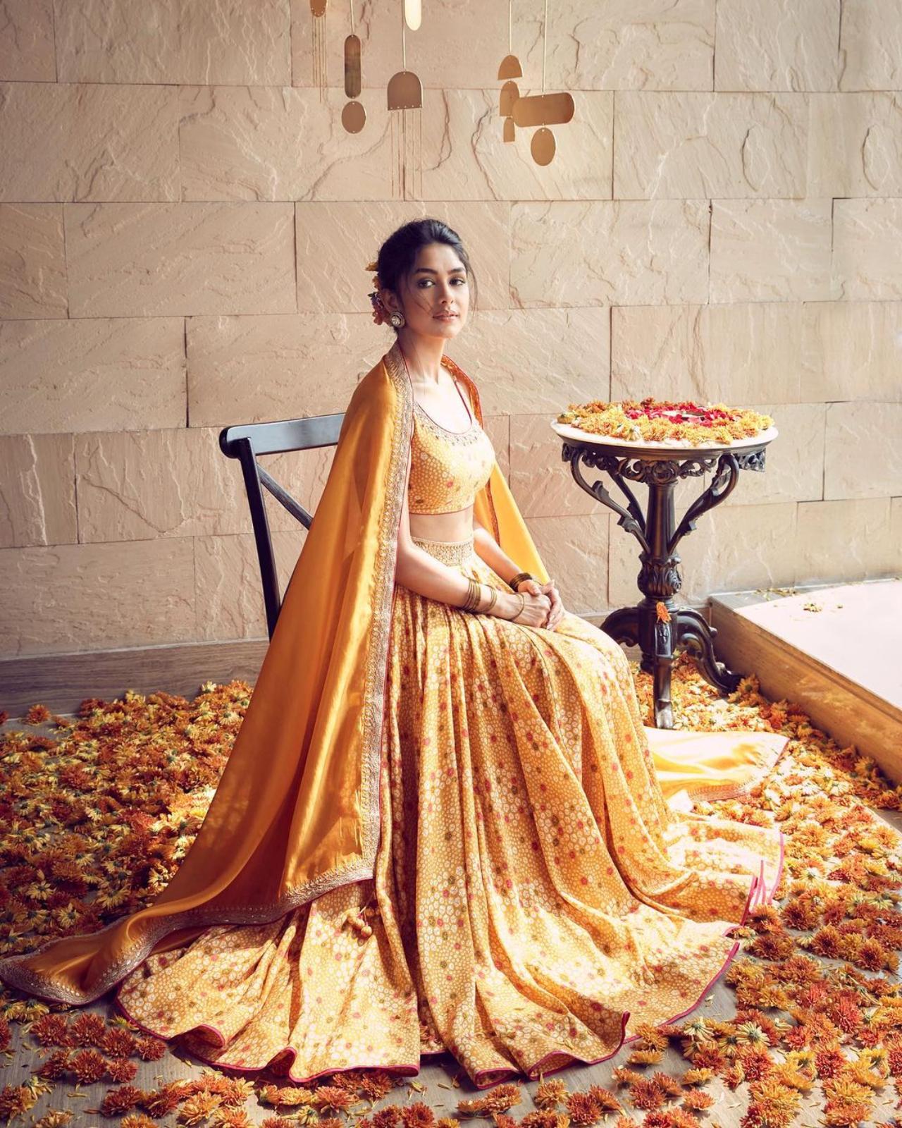 Mrunal Thakur
Mrunal Thakur opted for a mustard bandhani print lehenga set, complemented by an ornate blouse designed by Punit Balana. She enhanced the ensemble's richness by pairing it with a silk organza dupatta adorned with intricate marodi work. The sunshine filtering in through the window and the warm-tones aesthetics of the room elevated her traditional look even more