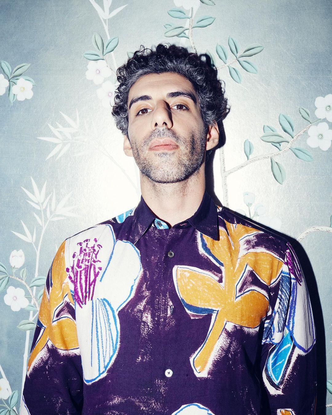 Sporting a unique and artistic ensemble, Jim Sarbh rocks a purple shirt adorned with intricate prints that resemble hand-drawn illustrations. The shirt's creative design adds an intriguing element to his outfit.