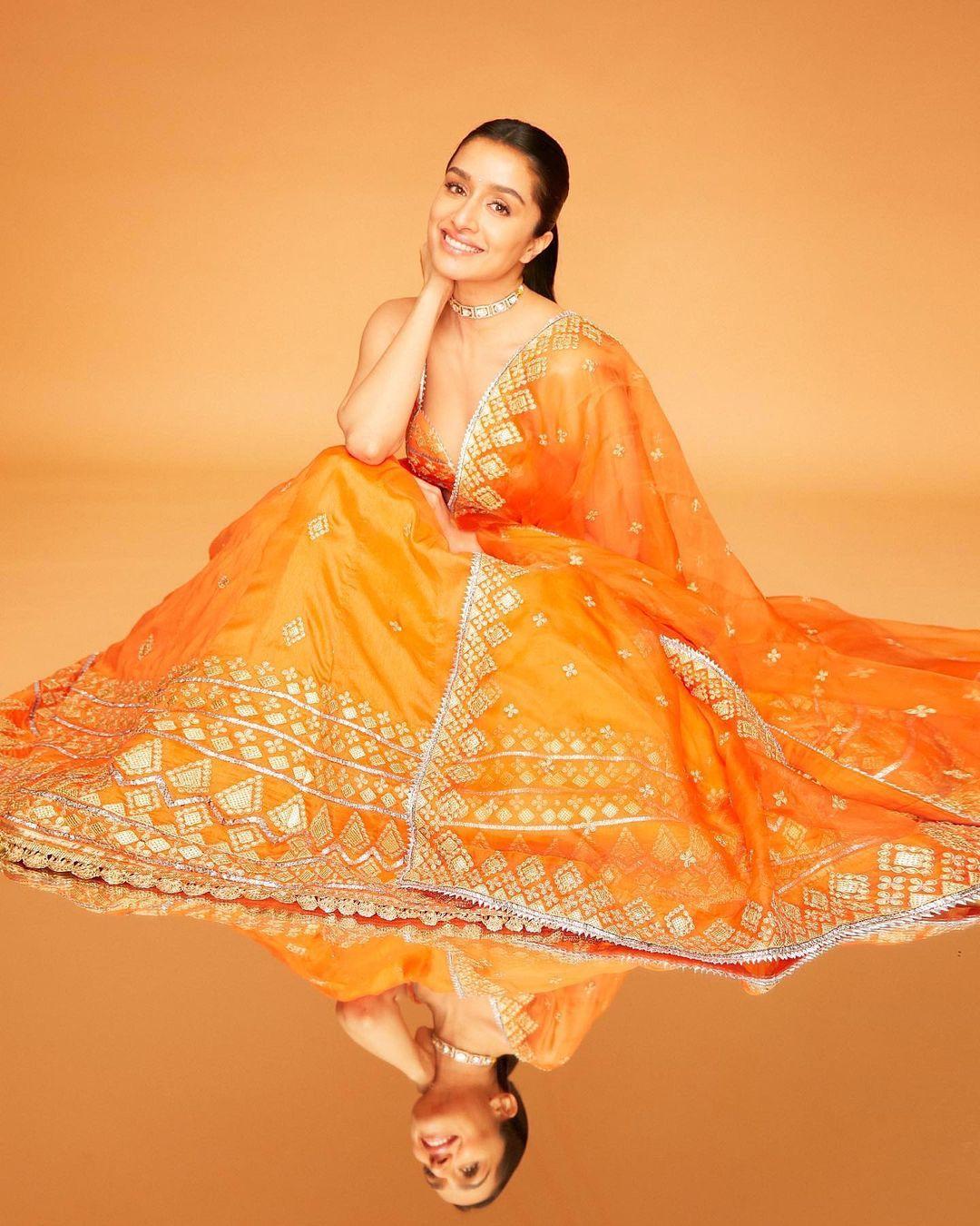 Shraddha Kapoor's choice of an orange lehenga radiates festive charm. The vibrant hue captures the spirit of celebration, while her elegant ensemble reflects a seamless blend of traditional and modern elements.