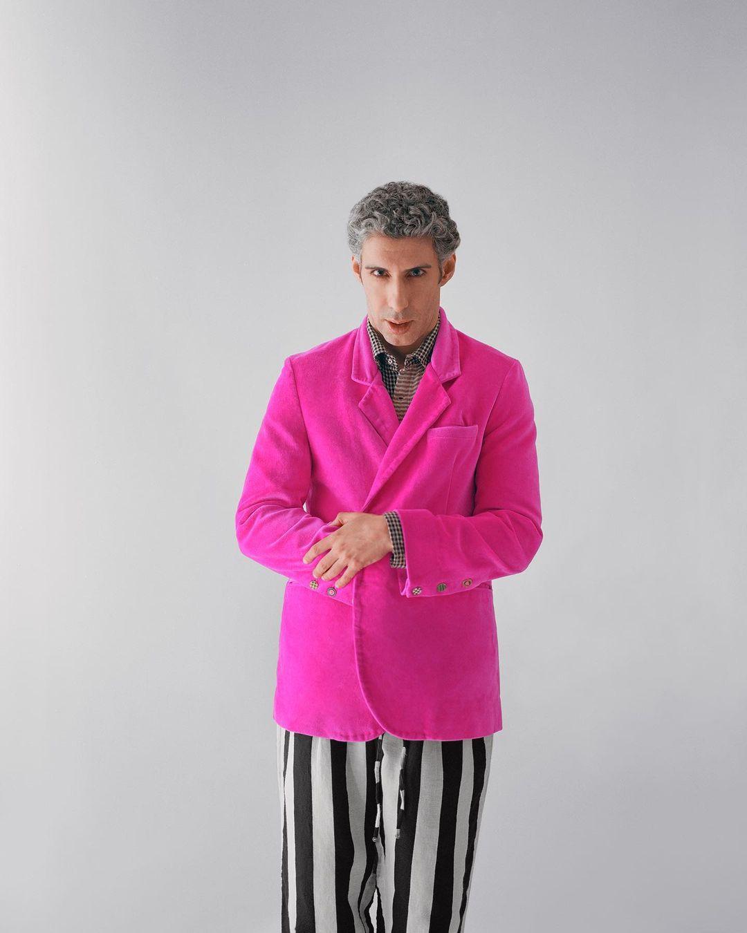 The pink coat adds a pop of color and vibrancy, while the pinstriped pants contribute a touch of sophistication to the overall look. 