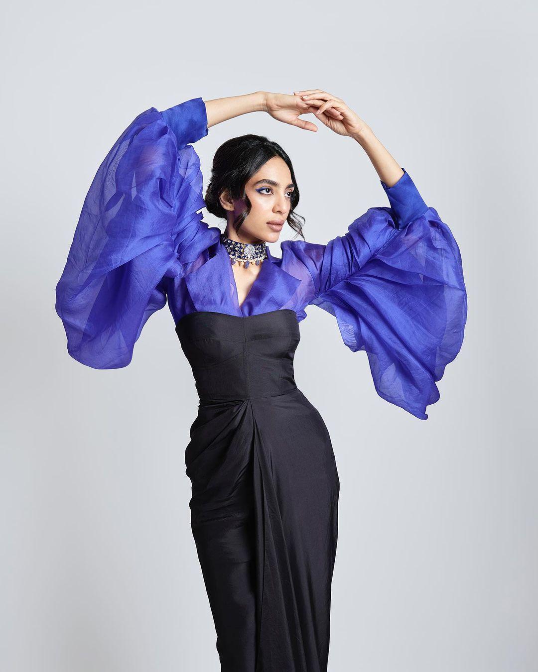 Her ensemble was elevated with a vibrant blue under-shirt featuring graceful outfly sleeves that added a touch of flair