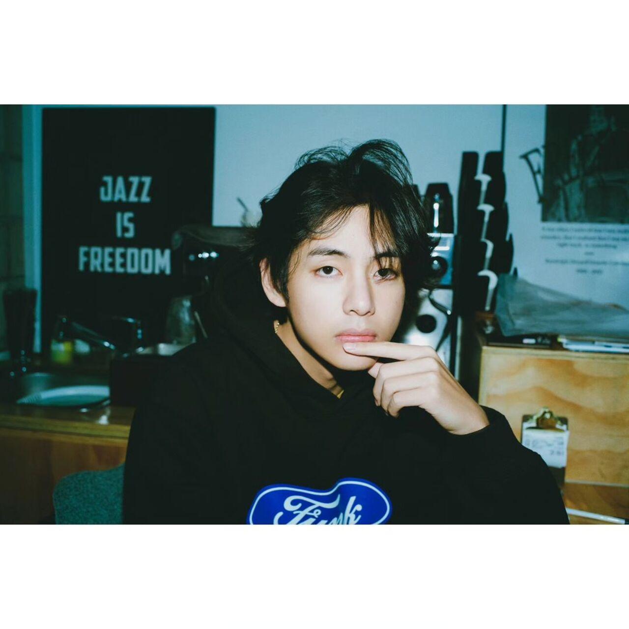 And as if right on cue, Taehyung poses in an understated black hoodie with 'Jazz is freedom' lettering in the background!