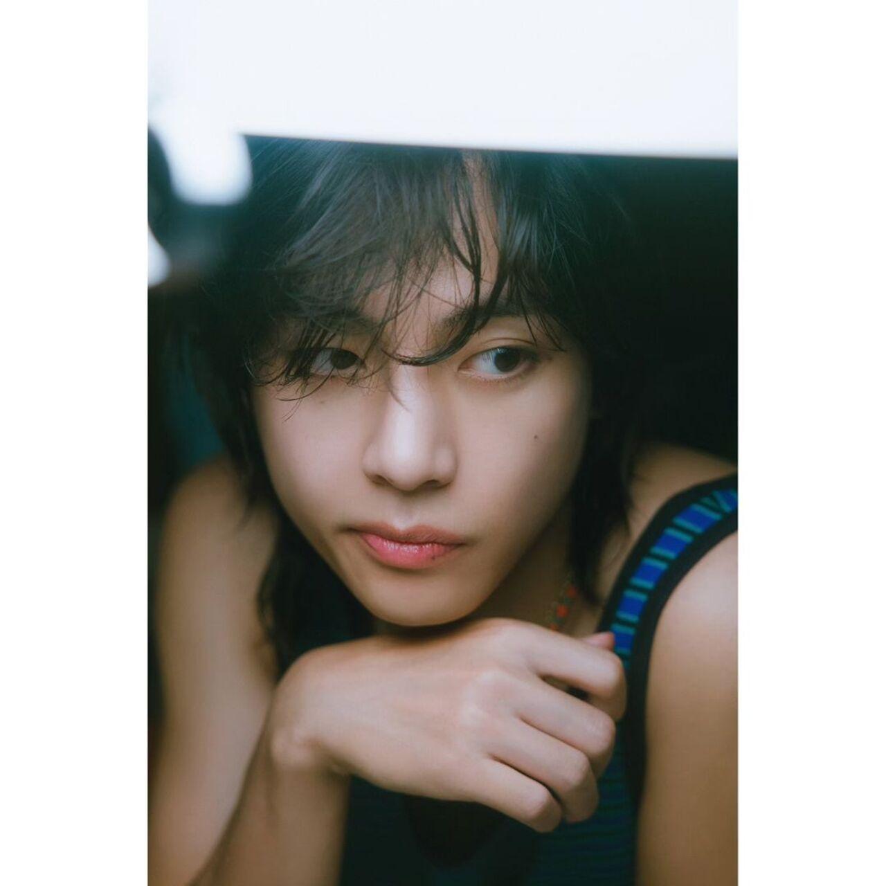 This photograph perfectly captures Taehyung's playful stylistic sensibililty. He looks super cute in his green-blue cool-toned tank top matched with some funky colouful neck jewellery