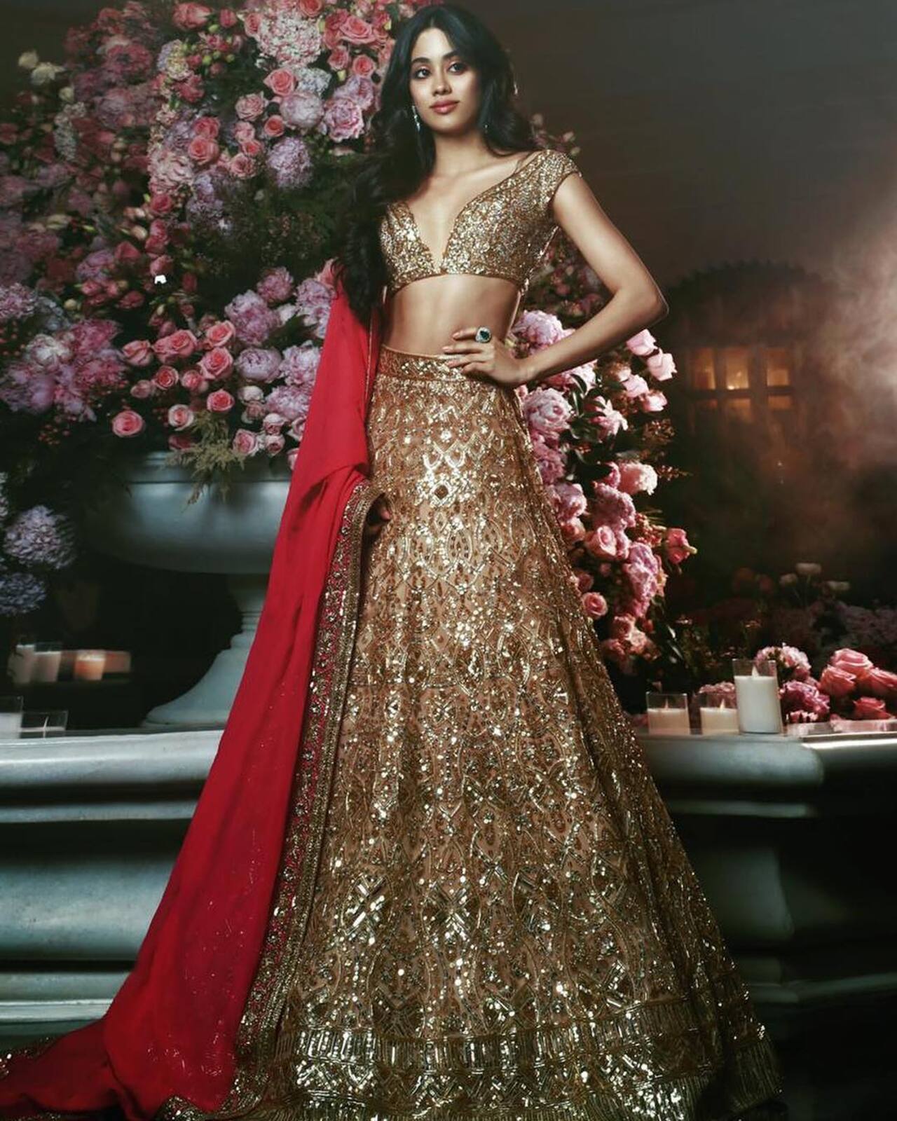 Janhvi definitely has a thing for Manish Malhotra outfits! She flaunted a gold lehenga by the fashion designer, highlighted with scarlet and detailed sequin embroidery. The A-line lehenga came with a matching blouse having a deep neckline. She paired it with a red dupatta with a gold border. Janhvi balanced the opulent outfit by wearing minimal jewelry. She chose emerald and diamond drop earrings and a matching ring