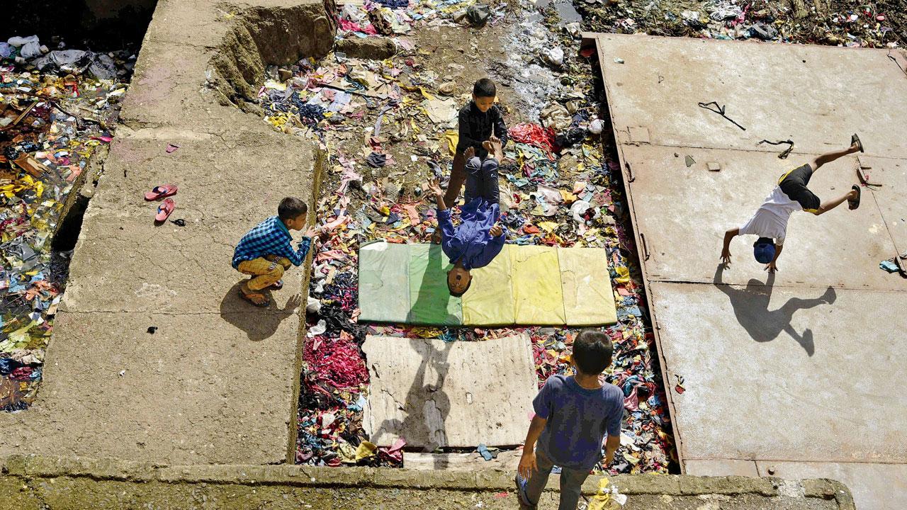 Kids set up their worn out gymnastic mats amid dirt and perform stunts in Bandra