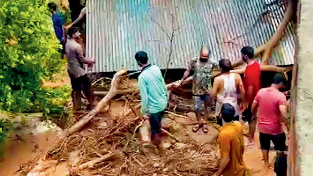 Locals remove fallen trees and muck that damaged houses at Kotla, in Kangra district.