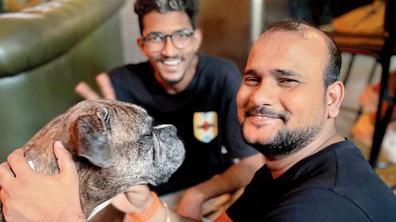 Two staff members of the eatery playfully pet Whiskey
