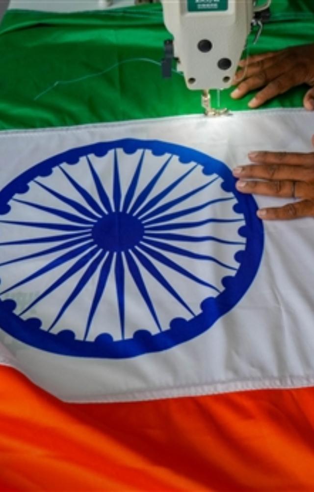 A worker stitches an Indian national flag