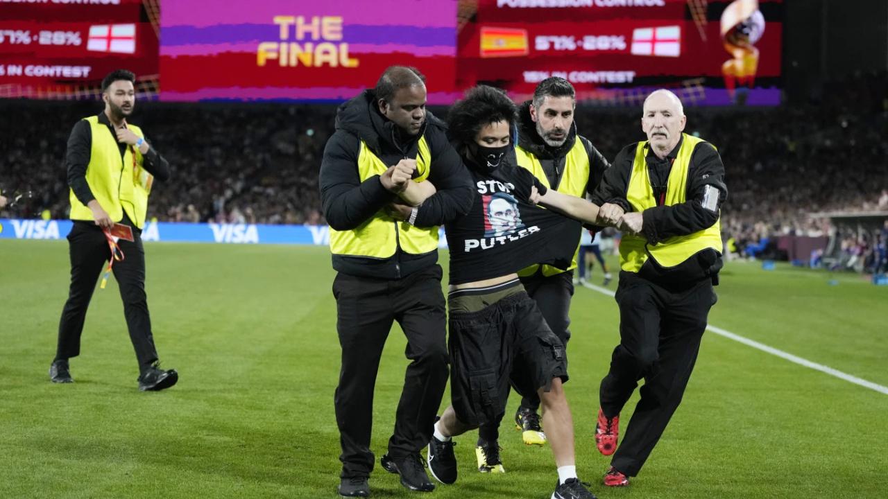 Security detain pitch invader wearing a t-shirt with an image showing Russian President Vladimir Putin as late German dictator Adolf Hitler during the final of Women’s World Cup soccer between Spain and England at Stadium Australia in Sydney, Australia, Sunday, Aug. 20, 2023. (AP Photo/Rick Rycroft)