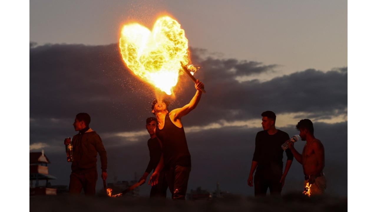 Palestinian youth show their fire breathing skills along the beach in Gaza City, on January 13, 2023. (Photo by MOHAMMED ABED/AFP)