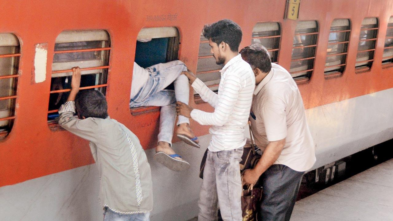 A man, helped by a friend, enters a passenger train through the emergency window of the Pawan express at LTT. Crowding on express trains became the most viral phenomena in 2023. Pic/Sayyed Sameer Abedi