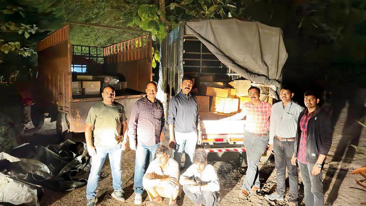 Officials pose behind 580 seized bottles of illicit liquor; excise department officials with Vikram Rajput and Sujanram Siya, who would allegedly sell illicit liquor