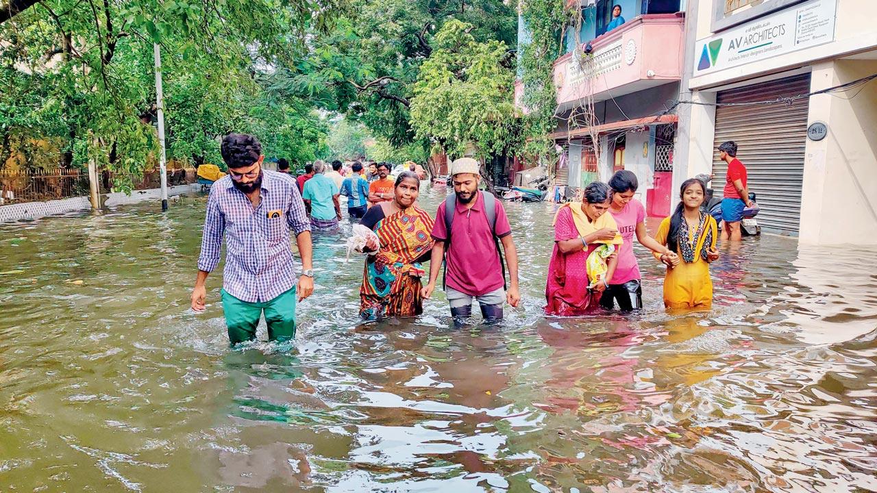 People wade through a flooded road in Chennai, on Tuesday. Pic/PTI 