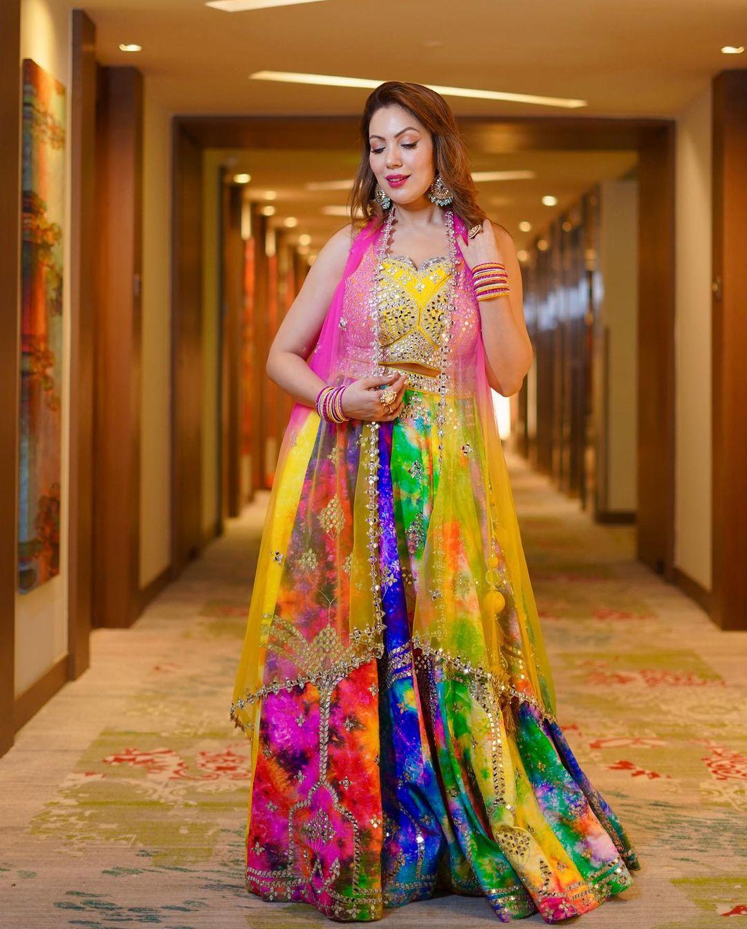 Hues of multi-colours and open hair are all that this wedding season calls for. The lehenga worn by Munmun is not too heavy but gives a rich look