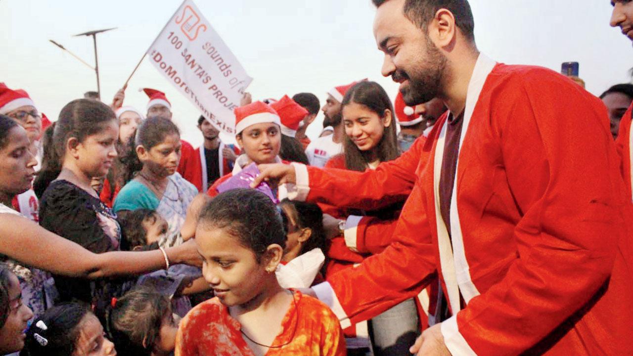 A volunteer dressed as Santa Claus distributes gifts 