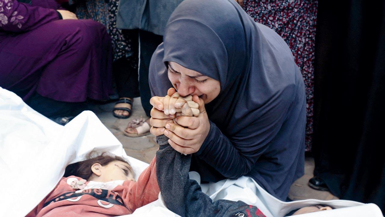 The mother of eight-year-old twins Ahmed and Jihan Nasser, who were killed during Israeli bombardment, kisses their hands as she mourns. Pics/AP
