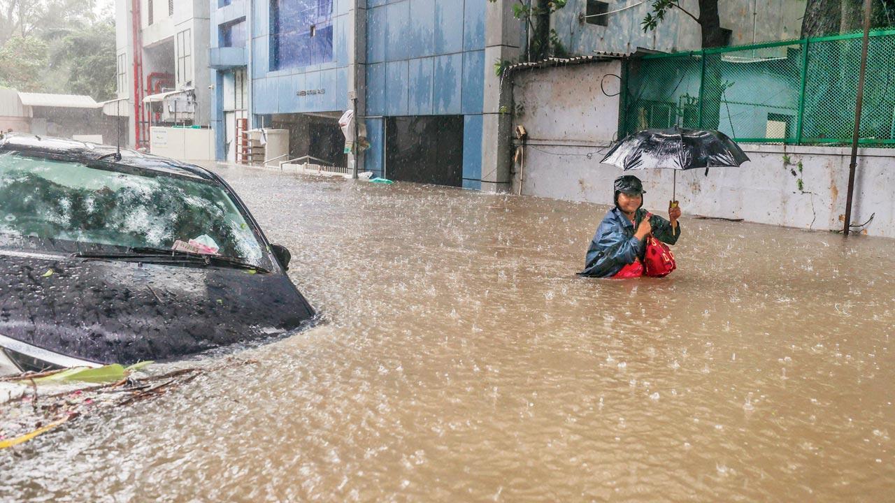 Commuters on a waterlogged road during heavy rain owing to Cyclone Michaung in Chennai