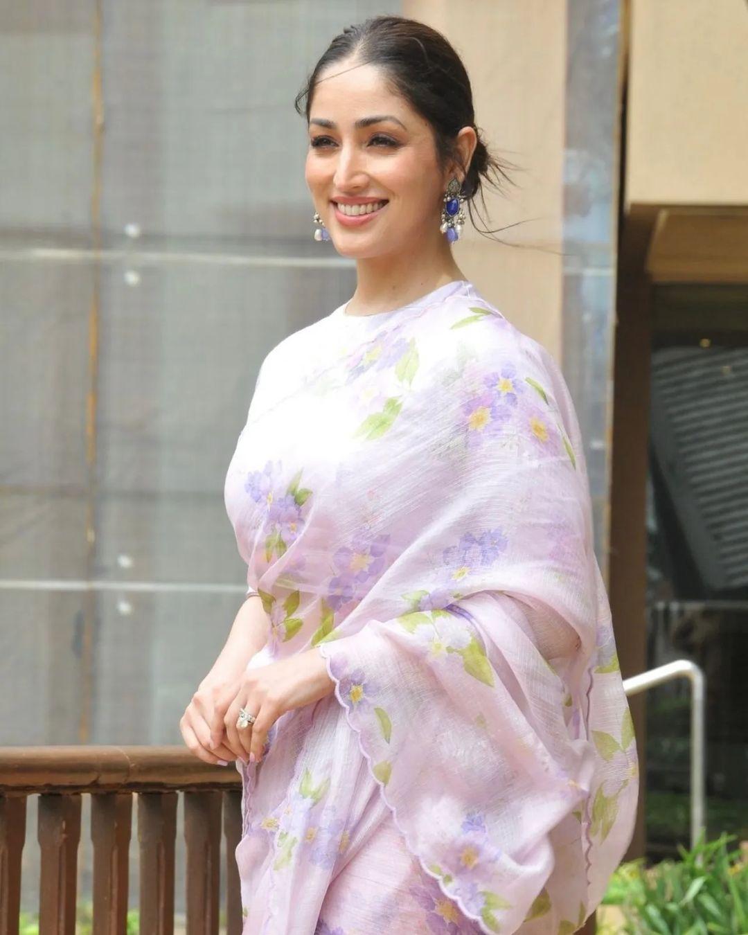 Yami is seen wearing a lavender-shaded organza saree with subtle floral prints. She has paired it with earrings in a darker shade and a no-makeup look
