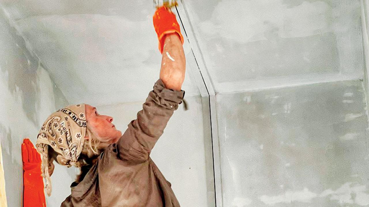 A volunteer paints the ceiling in the classroom