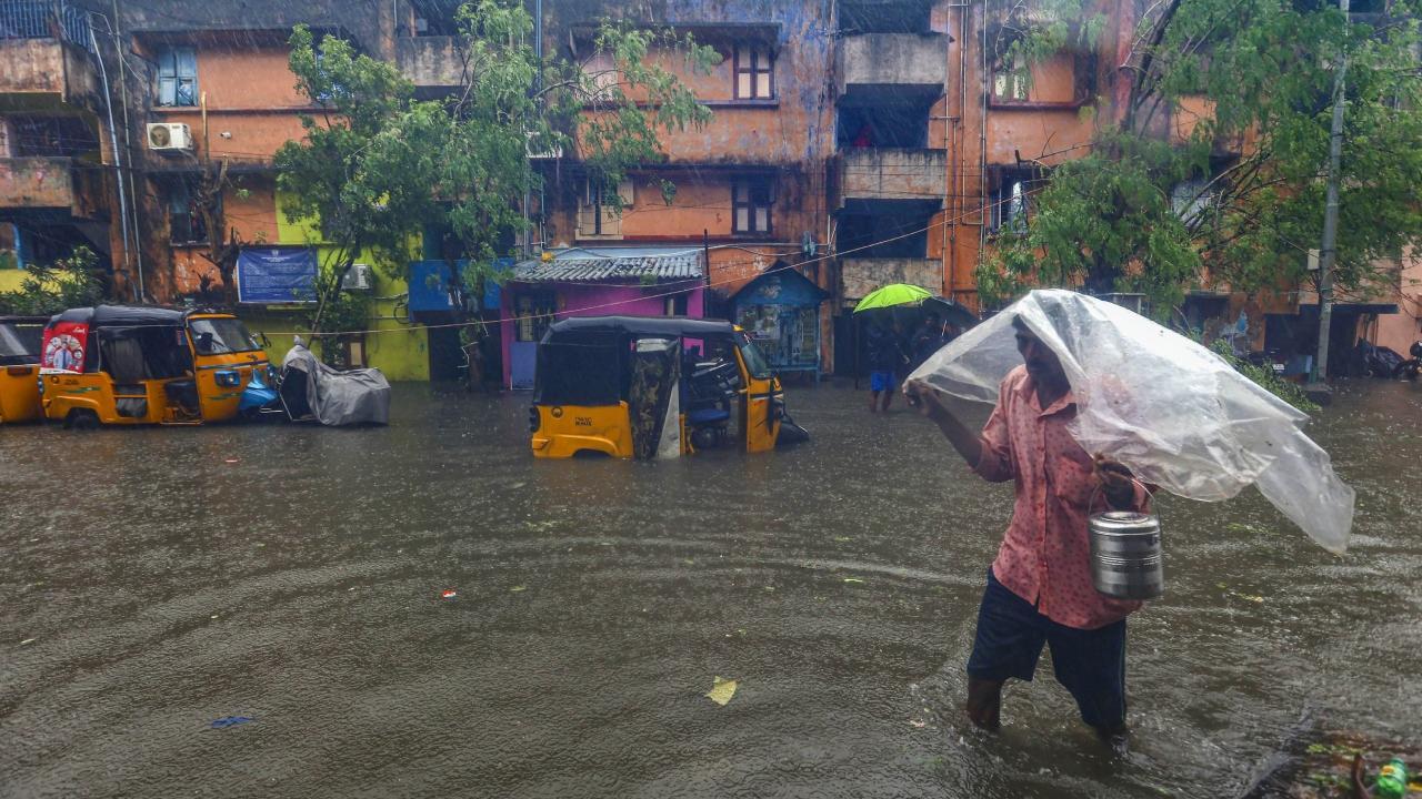 A local wades through a waterlogged road during heavy rain owing to Cyclone Michaun in Chennai. Pics/PTI