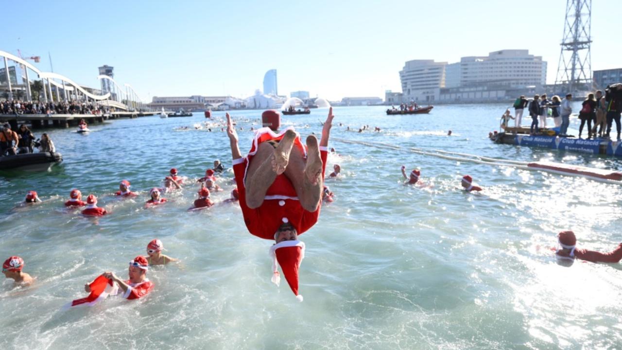 A participant in Santa Claus costume jumps into the water during the 114th edition of the Copa Nadal (Christmas Cup) swimming race in Barcelona's Port Vell on December 25, 2023. The traditional 200-meter Christmas swimming race gathered around 300 participants on Barcelona's Port Vell (old harbour). (Photo by Josep LAGO/AFP)