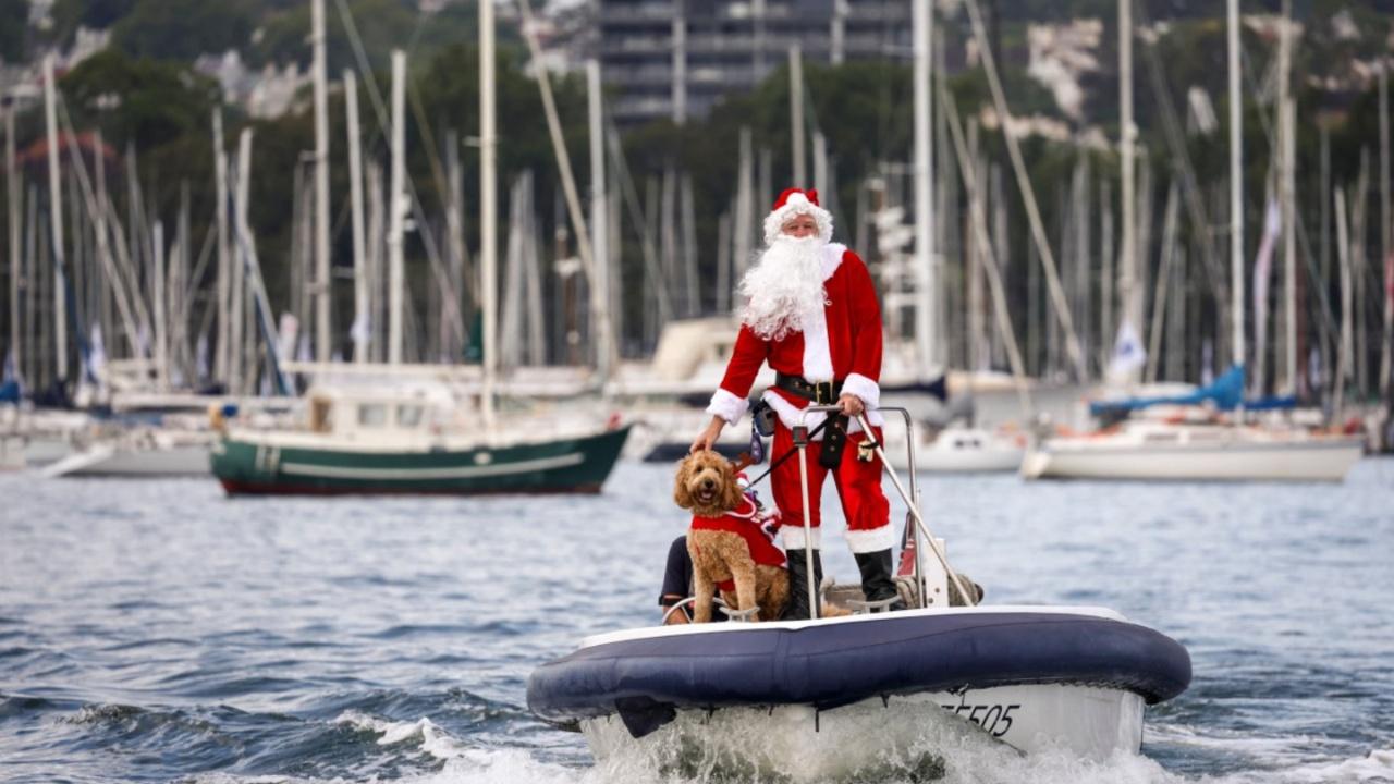 A man dressed as Santa Claus rides a boat with his dog in front of the Sydney Opera House, as part of Christmas Day celebrations for the annual Sydney to Hobart yacht race on December 25, 2023. (Photo by DAVID GRAY/AFP)